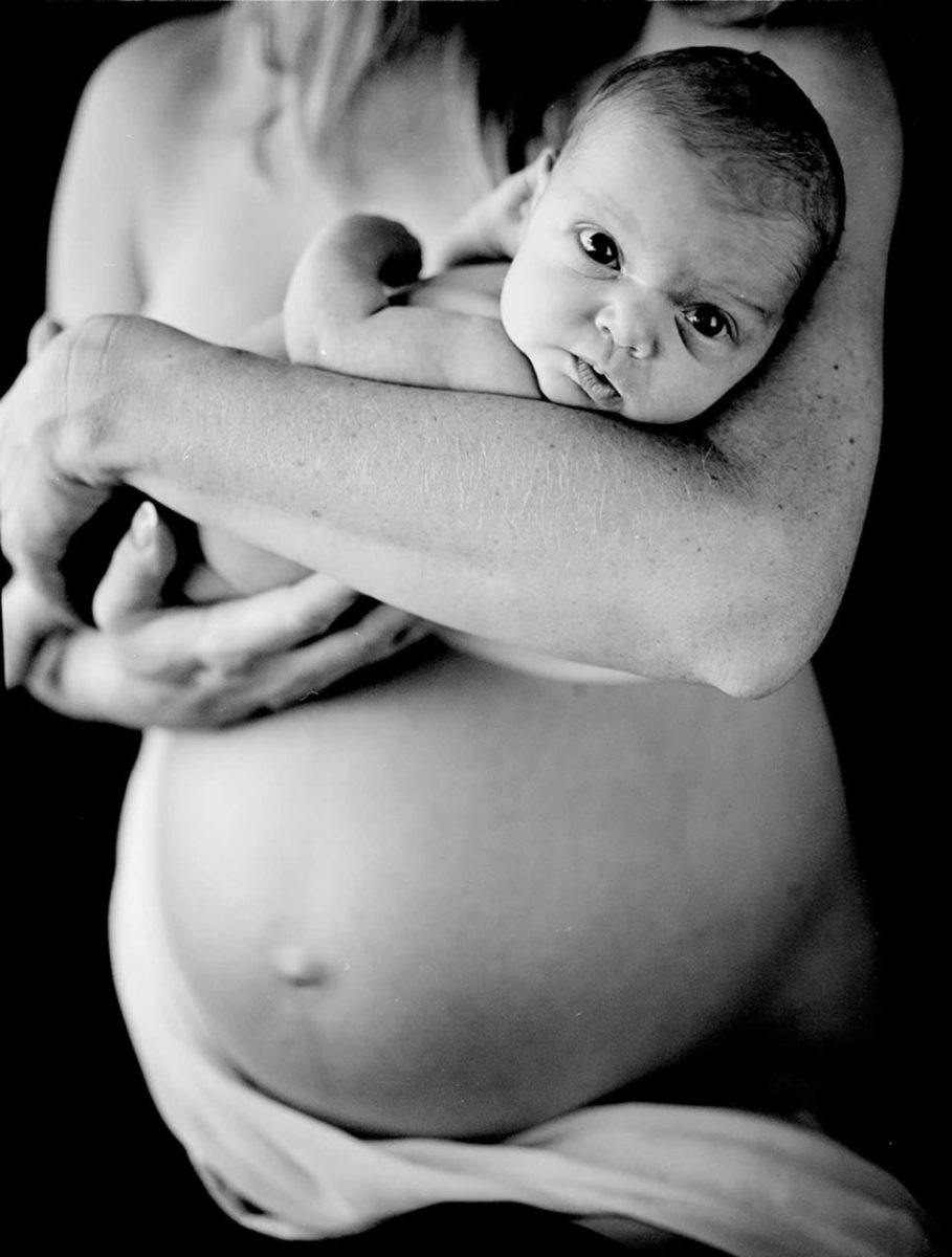 A pregnant woman holding her sister's newborn. Canada.
