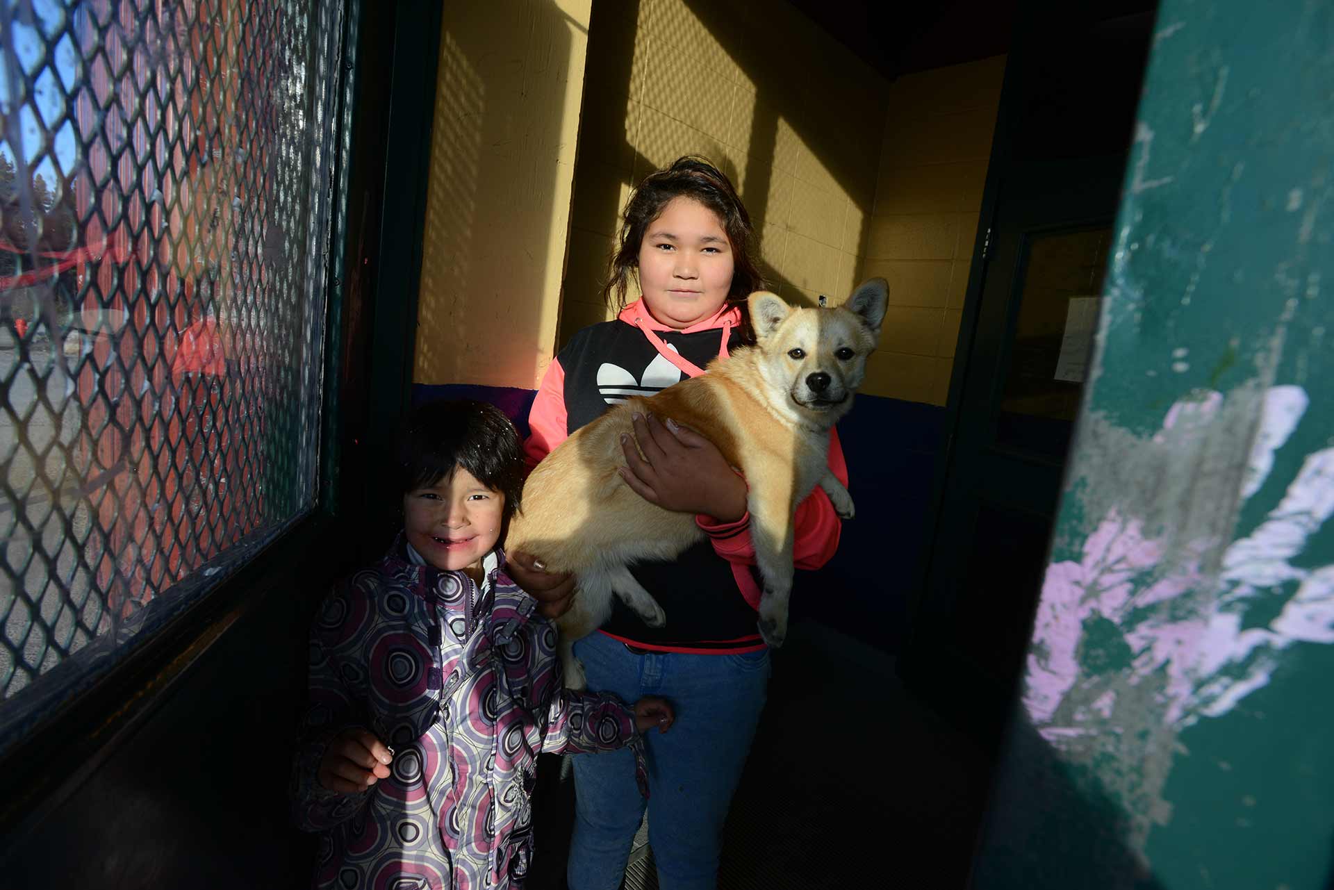 Children in the Indigenous community of Opitciwan carry a dog to the travelling veterinary clinic.